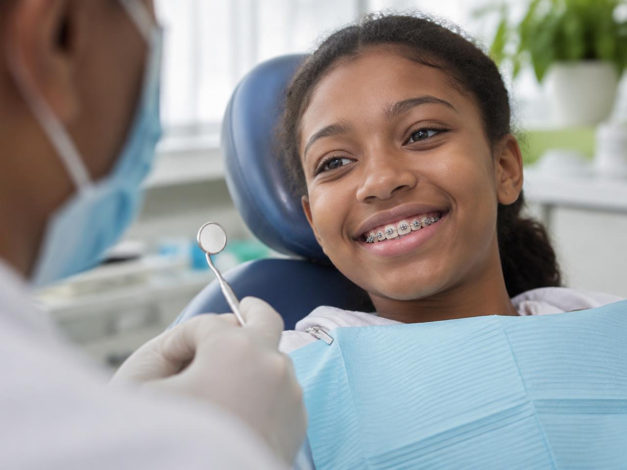 Adolescente souriante portant des appareils orthodontiques dans un cabinet dentaire.